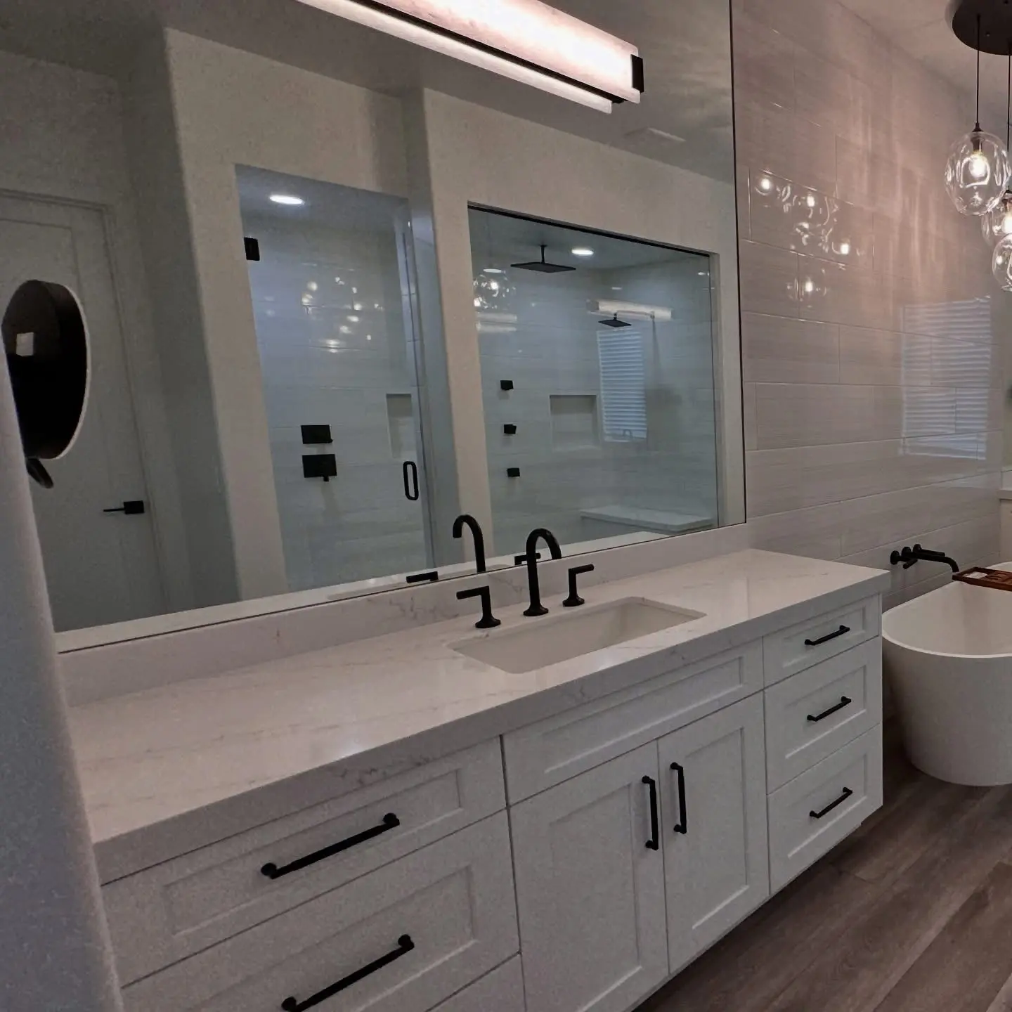 White vanity with black fixtures and a freestanding tub in a Masizo bathroom