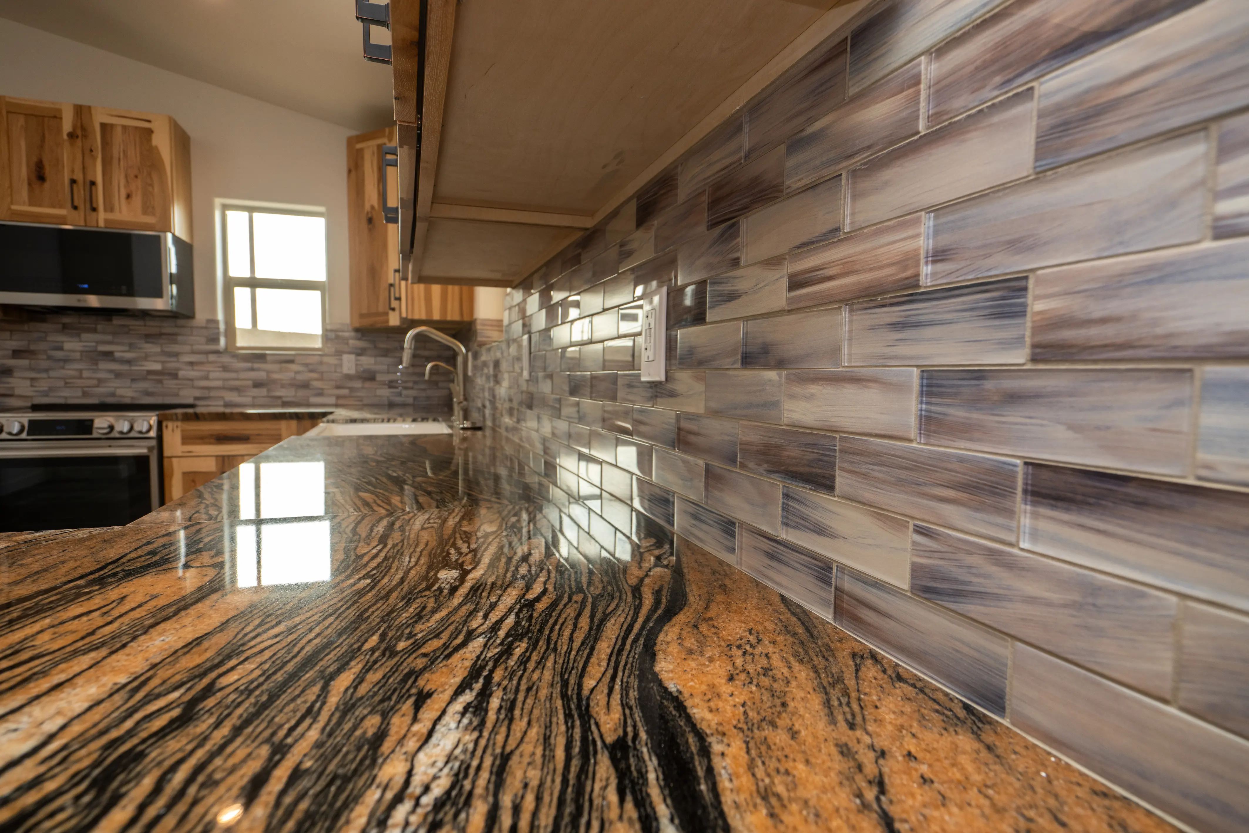 Granite countertop and glass tile backsplash in a kitchen on a Masizo remodel