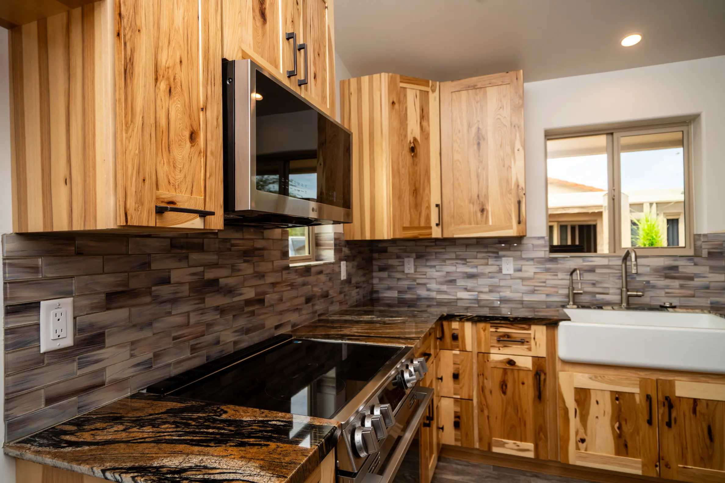 Hickory cabinets with granite counters and a tile backsplash in a Masizo kitchen