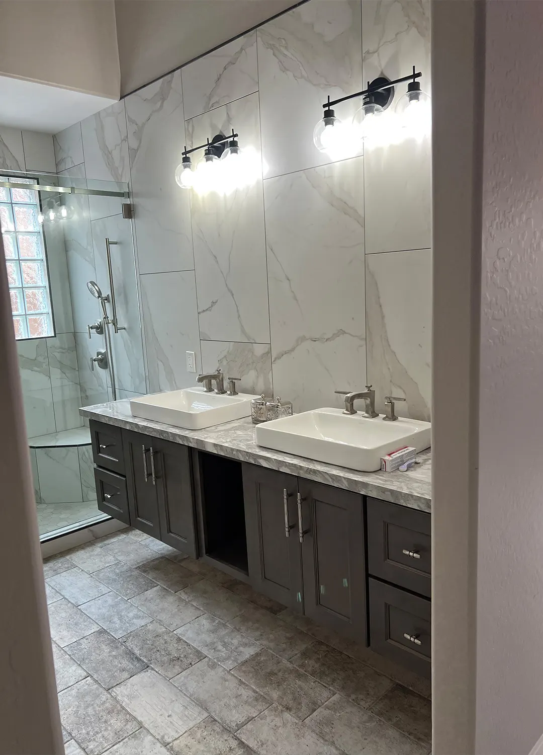 Double vanity with two vessel sinks next to a glass shower in a Masizo bathroom