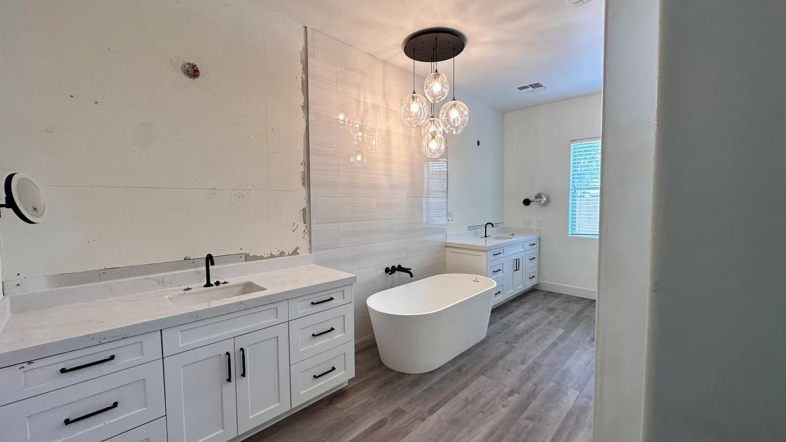 Freestanding tub under a pendant light in a remodeled Masizo bathroom