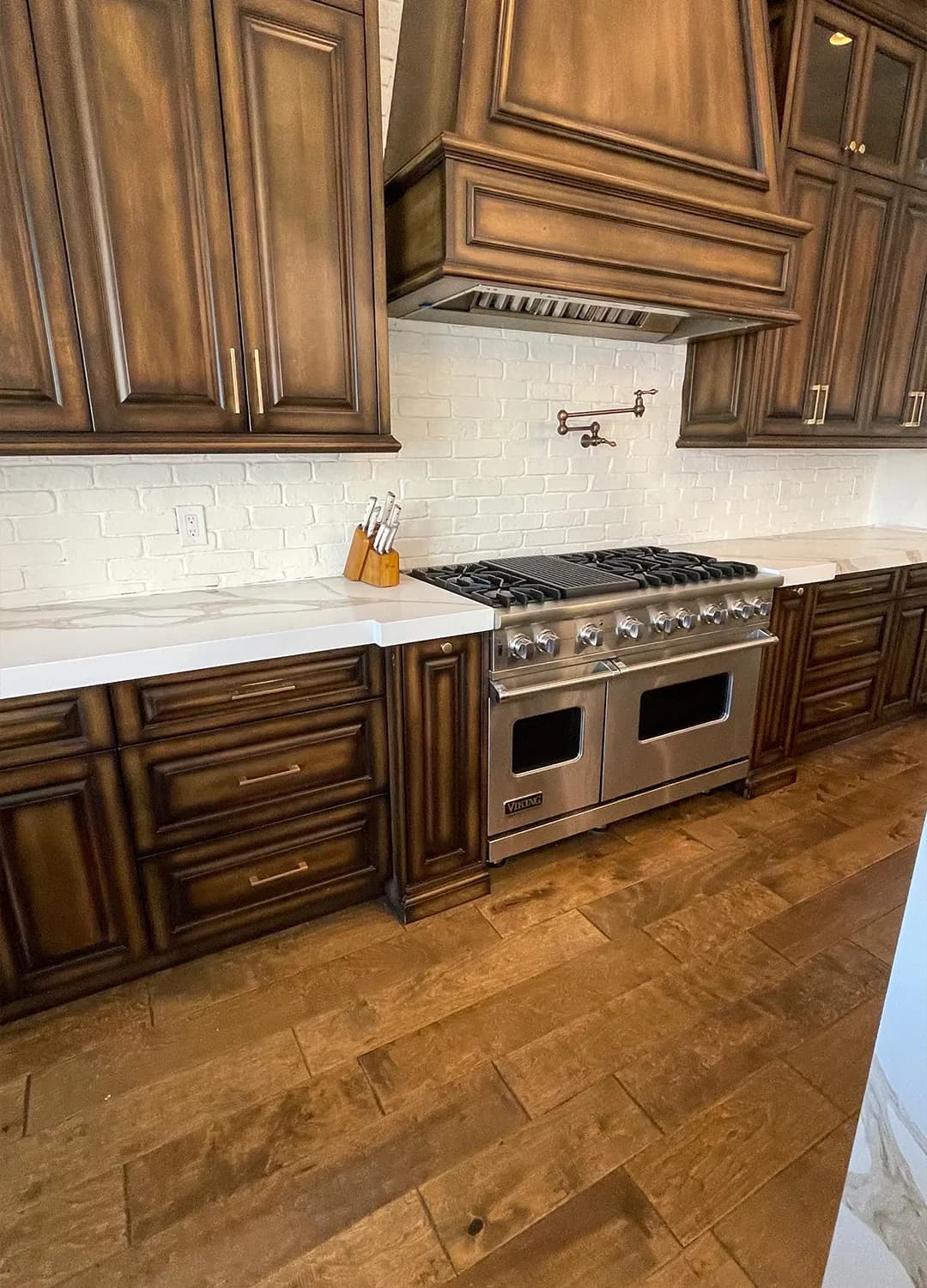 Dark wood cabinets, a wood hood and a steel range in a Masizo kitchen