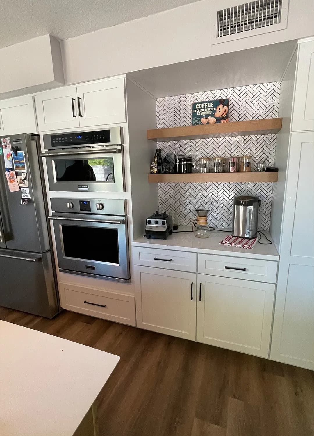 White kitchen with stacked wall ovens and open shelves on a Masizo job