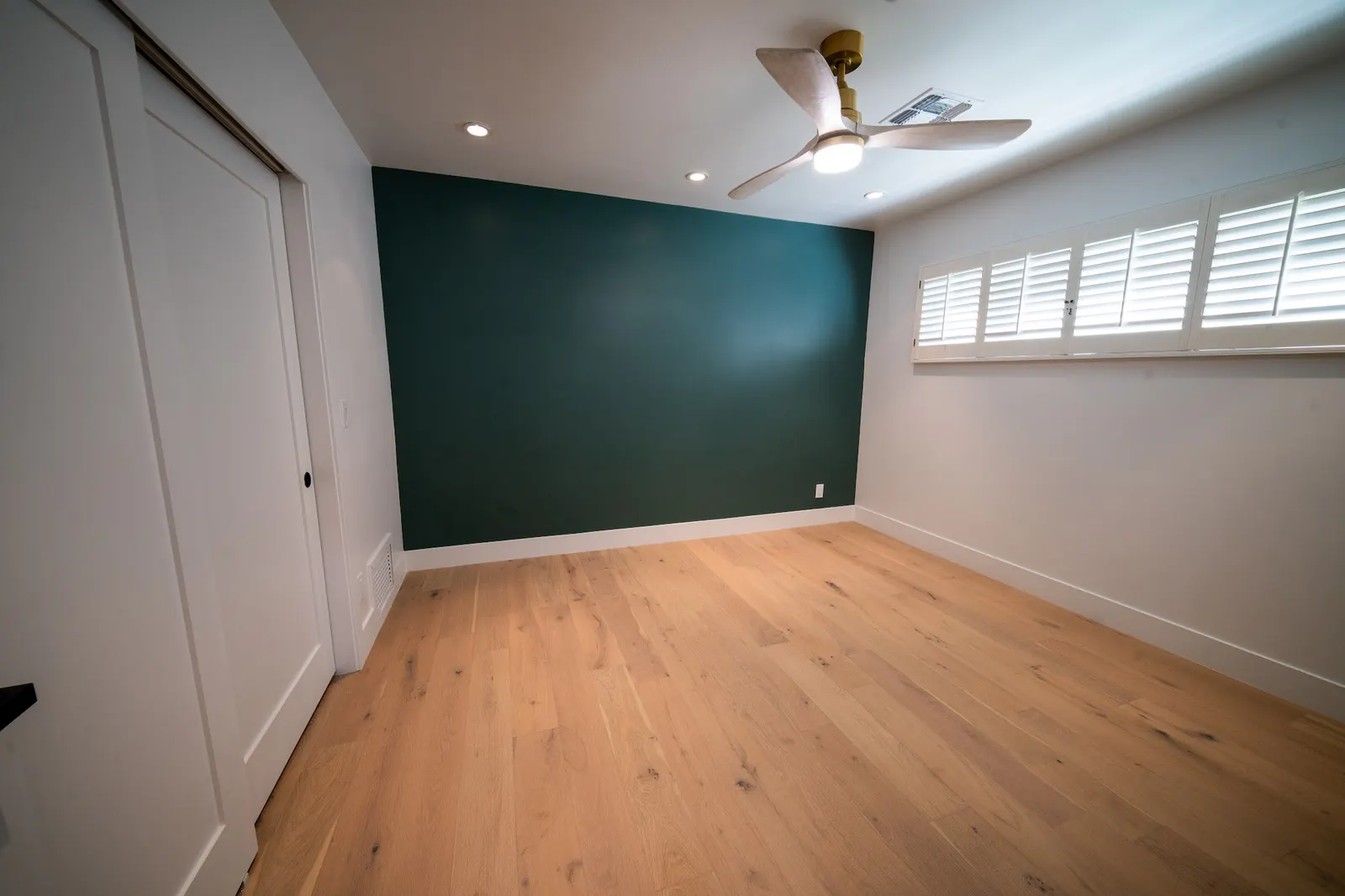 Bedroom with a green accent wall and wood floors on a Masizo job