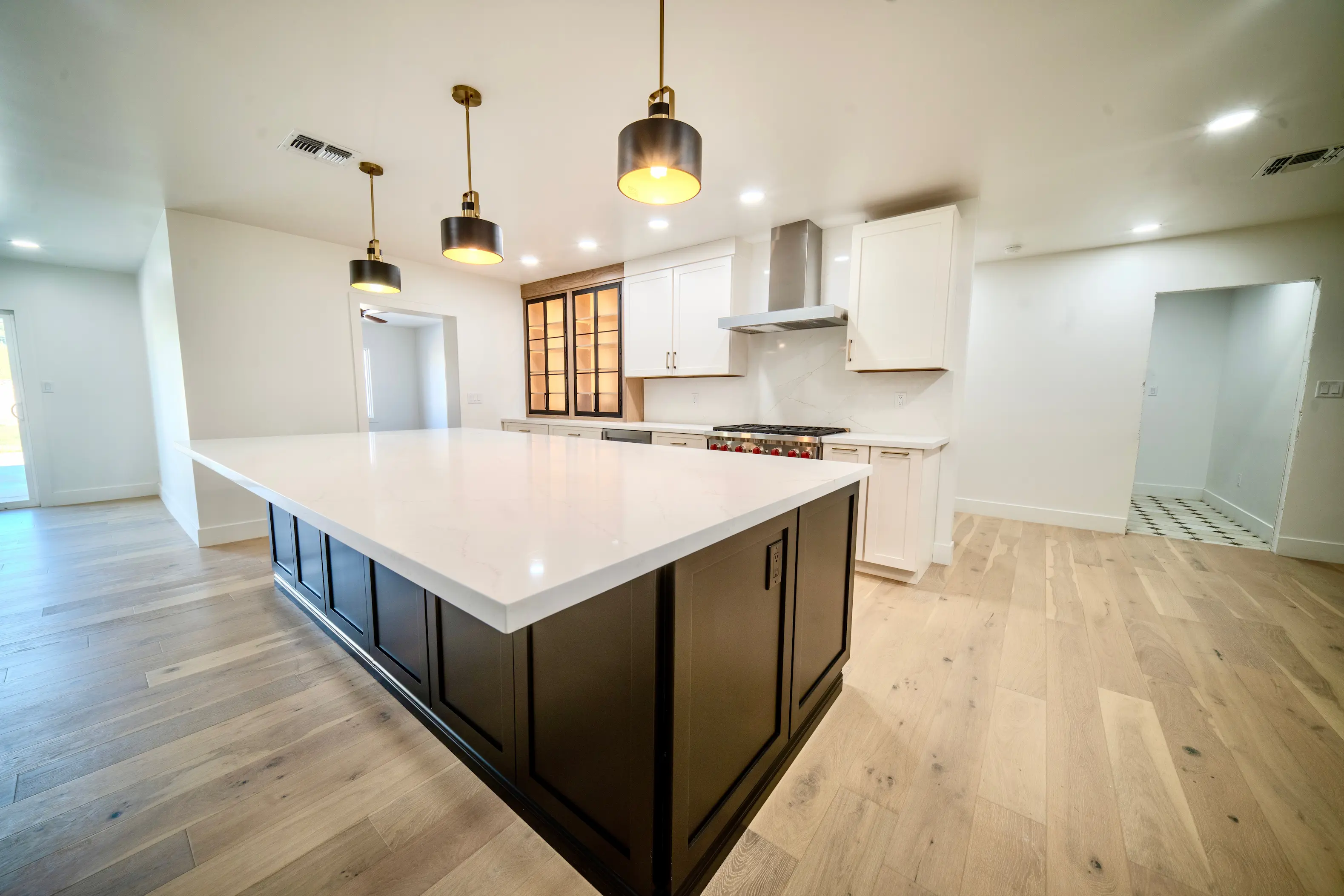 Open kitchen with a dark island, white cabinets and wood floors