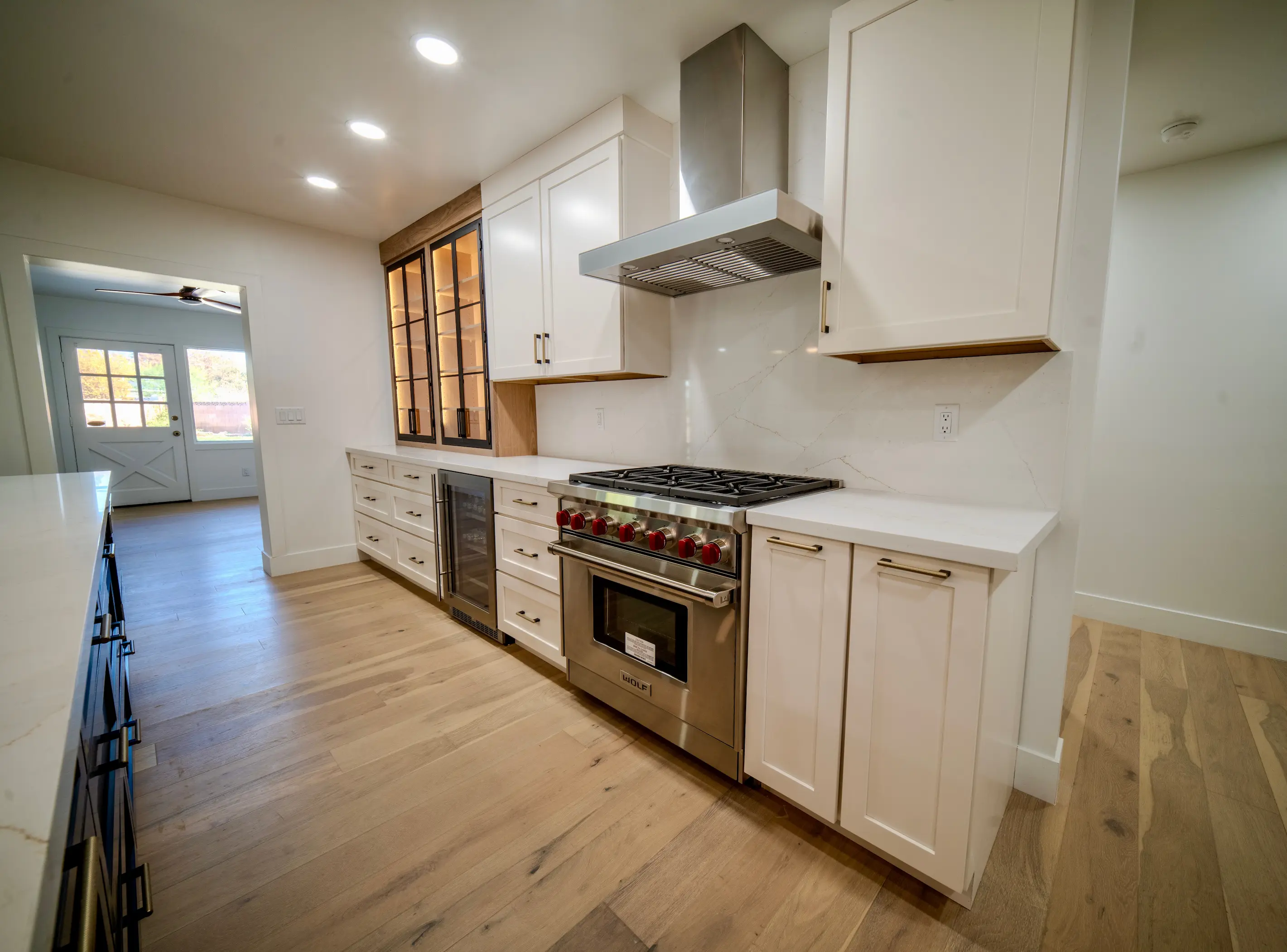 Remodeled kitchen with white shaker cabinets and a stainless range hood