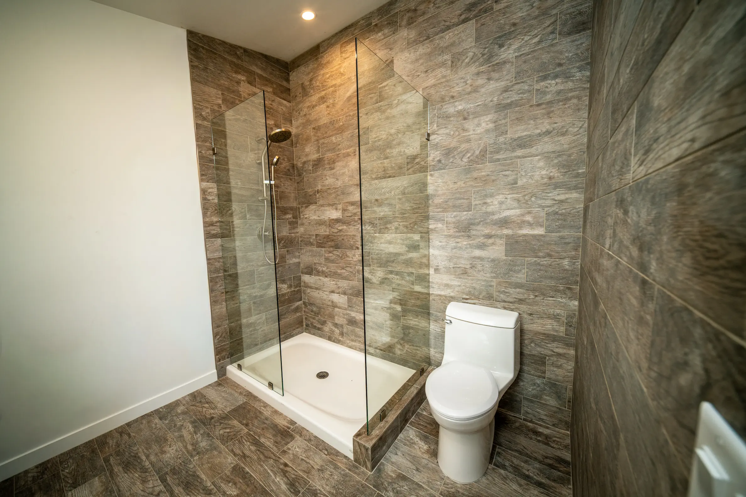 Walk-in tile shower with a glass panel in a remodeled bathroom