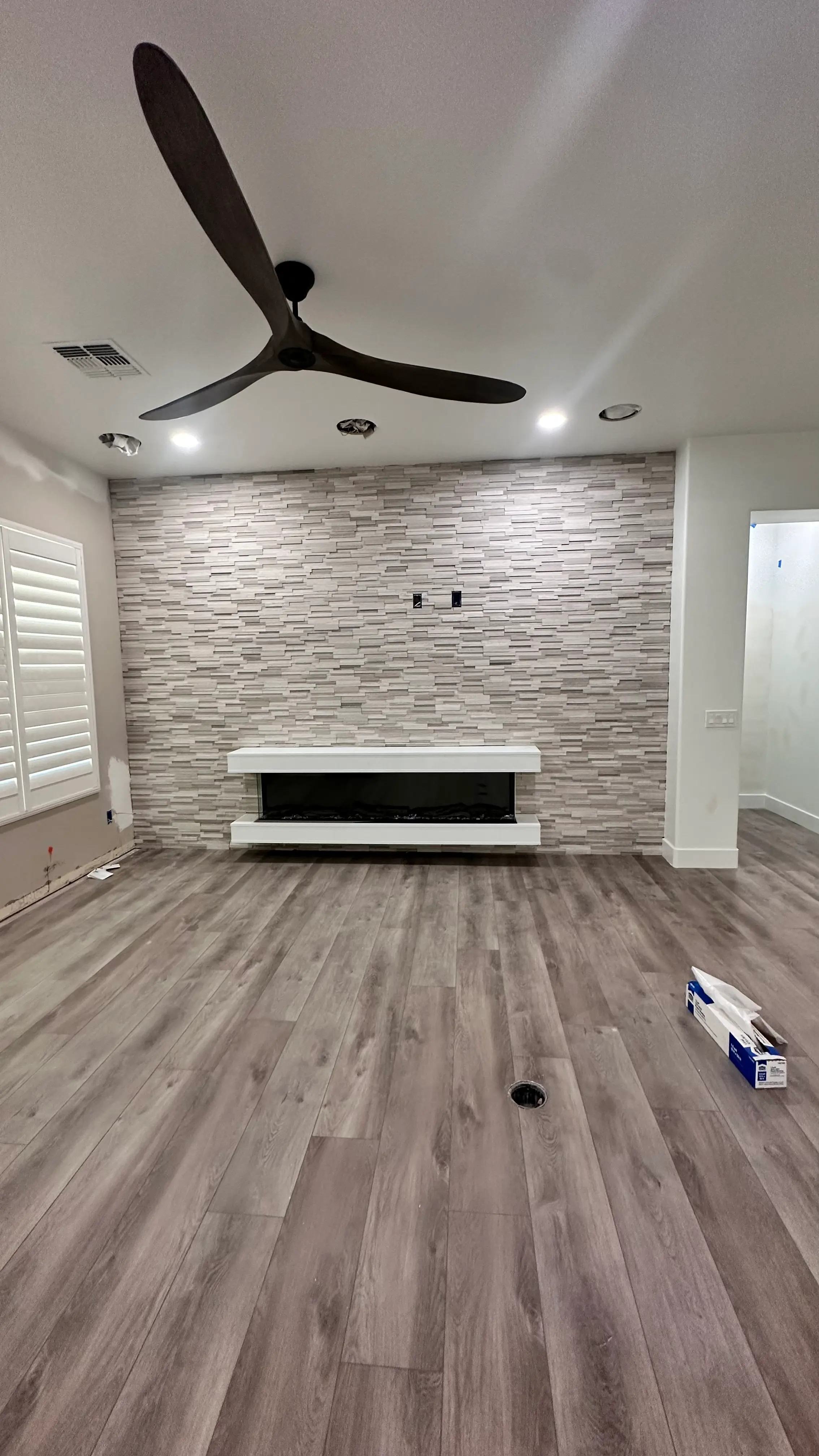 Living room with a stone fireplace wall and a ceiling fan